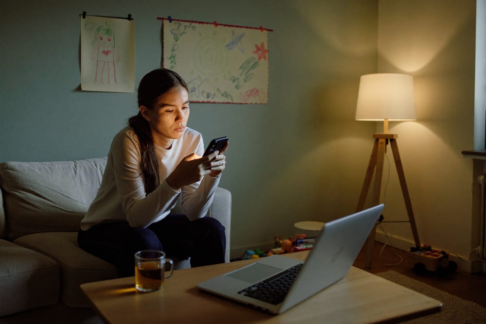 Mutter sucht abends auf dem Handy nach Sprachübungen für ihr Kind